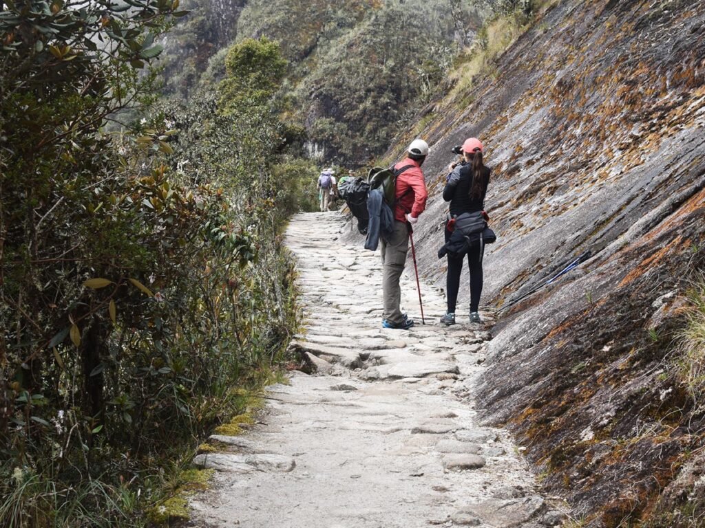 Dos caminantes sobre el empedrado inca del sendero hacia Machu Picchu