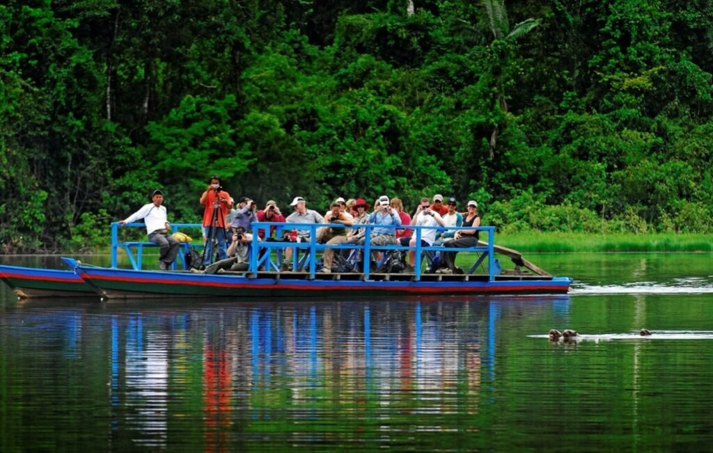 Visitantes en una embarcación de madera sobre un lago de la selva de Tambopata, en ruta hacia la collpa de guacamayos