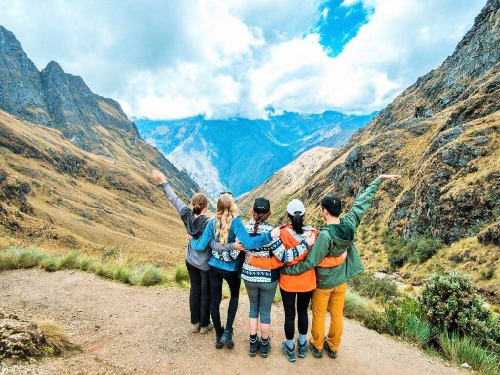 Grupo de viajeros con los brazos abiertos en un sendero de montaña de la ruta inca hacia Machu Picchu
