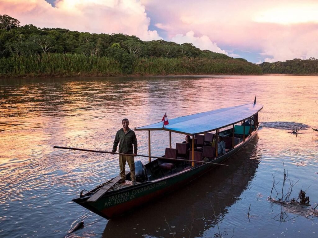 Bote navegando por el río Alto Madre de Dios al atardecer en el viaje al Manu desde Cusco