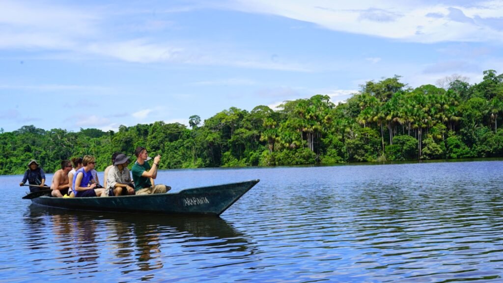 Grupo de viajeros en canoa sobre un lago rodeado de selva, con la ropa ligera que conviene llevar a la selva